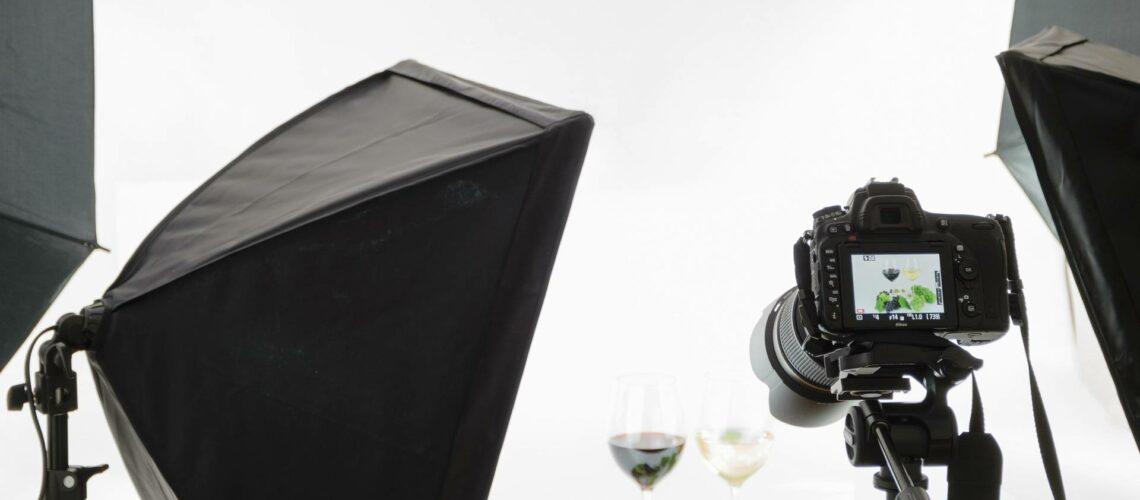 A set of photography equipment with a camera and a glass of wine.