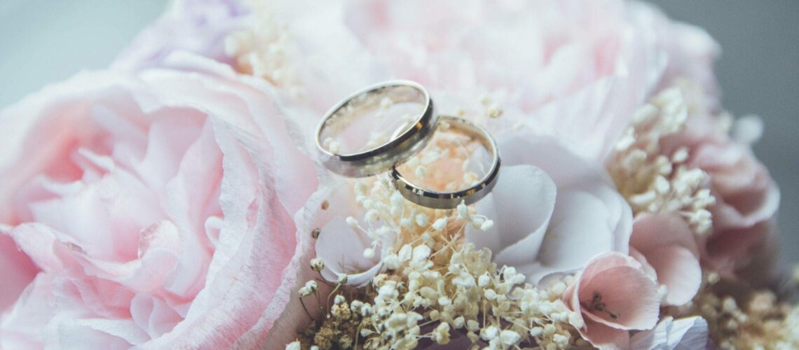 Two wedding rings on a bouquet of pink flowers.