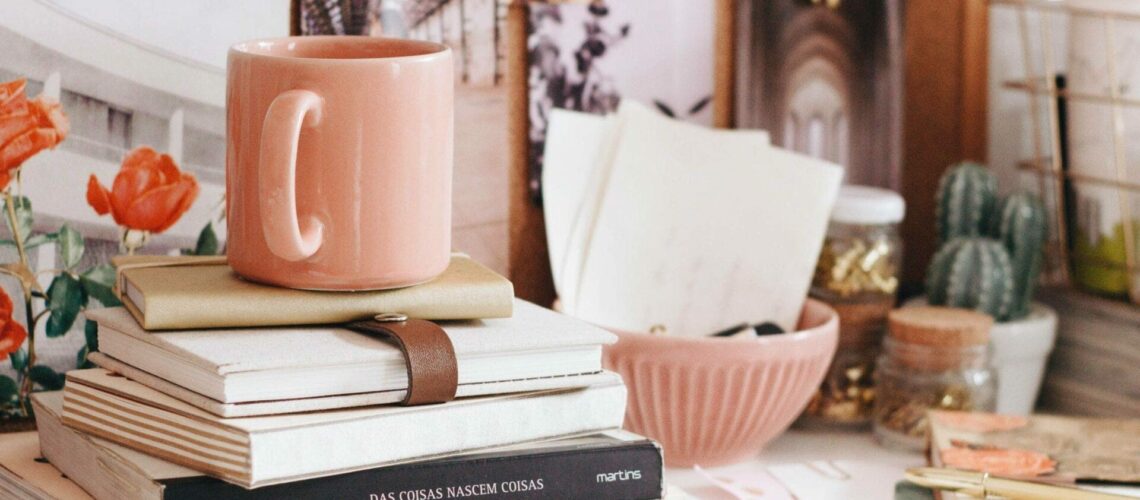 A desk with books, a mug, and a cactus.