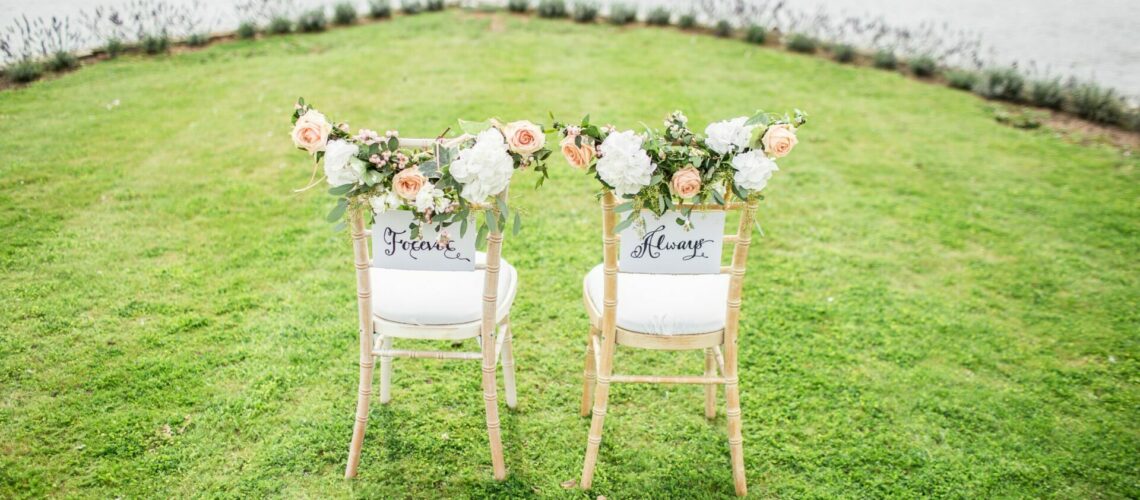 Two chairs are sitting on the grass next to a lake.