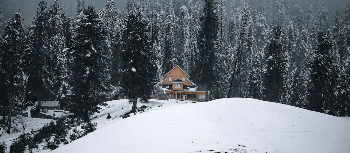 A house is sitting on top of a snow covered hill.