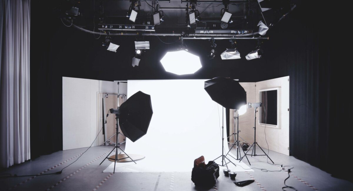 A black and white photo studio with lights and a tripod.